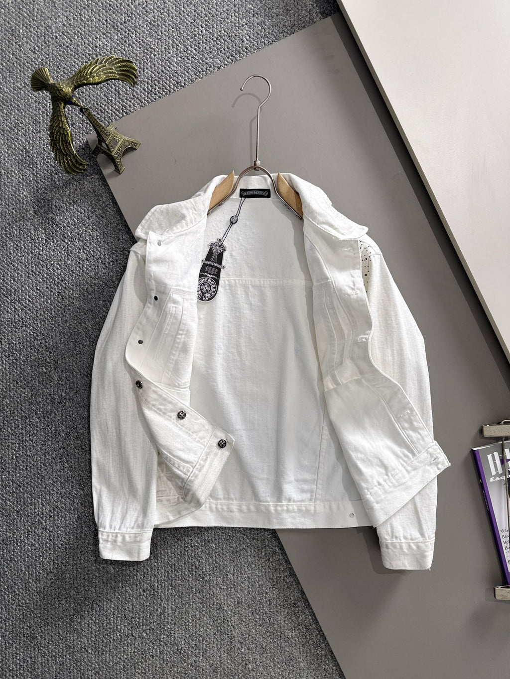 White denim jacket with black dot pattern, chest pockets, and button front on hanger