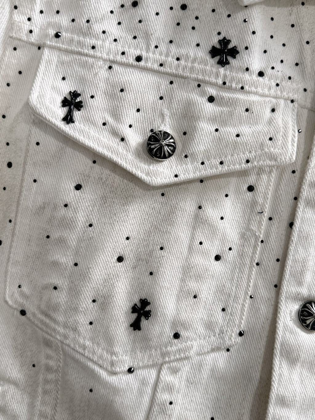 White denim jacket front with black dot pattern, star appliques, and round decorative button