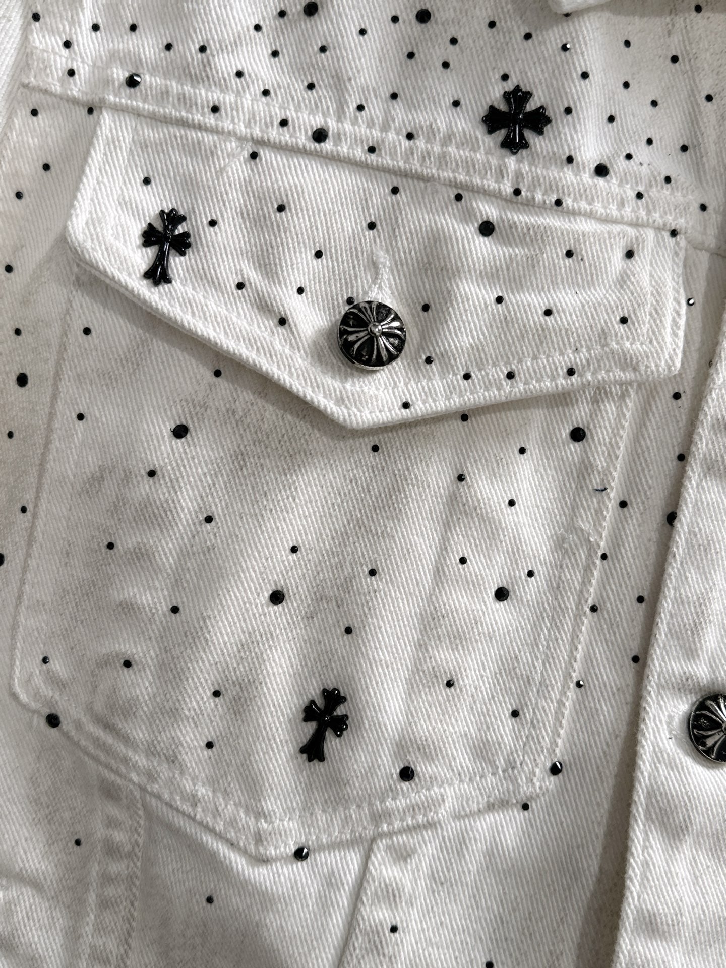 White denim jacket front with black dot pattern, star appliques, and round decorative button