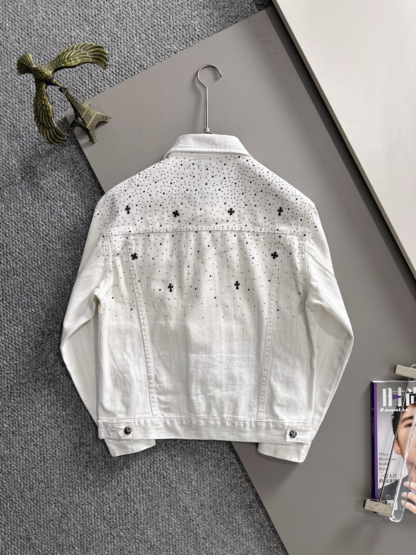 White denim jacket back view with black dot pattern, denim button front, on hanger