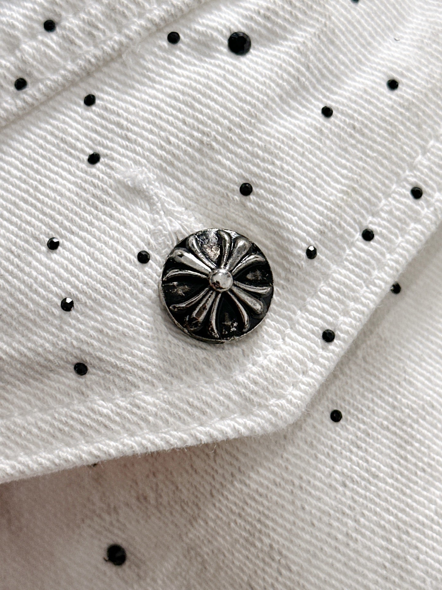White denim fabric with black dot pattern and round black decorative button