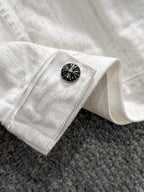 White denim jacket sleeve cuff with black decorative button and folded hem