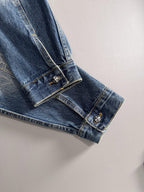 Blue denim jacket sleeve cuff with stitched emblem patch and pearl button detail