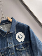 Blue denim jacket close-up with pearl-embroidered round emblem on chest pocket