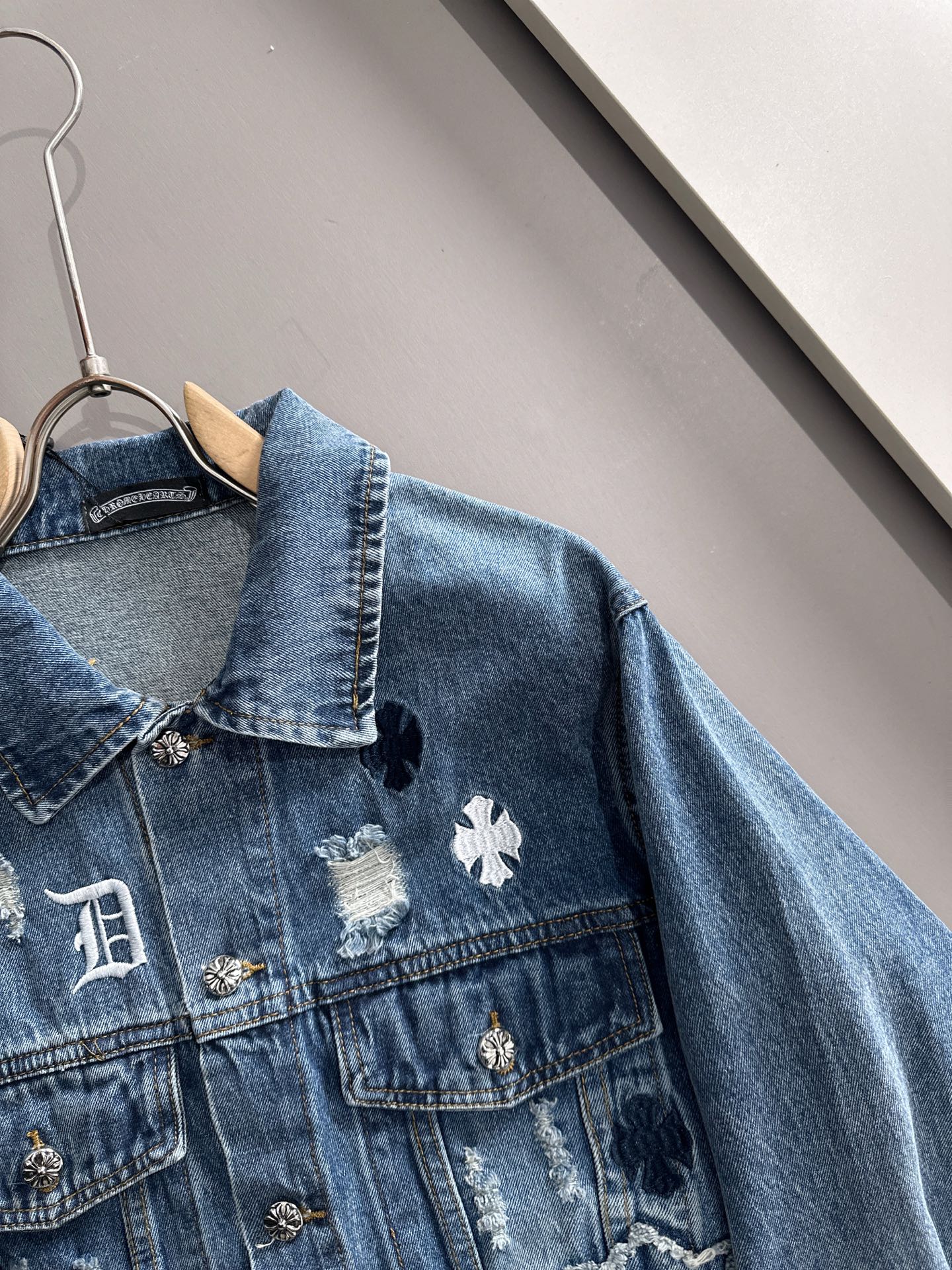 Blue denim jacket with embroidered cross patch and scalloped collar detail