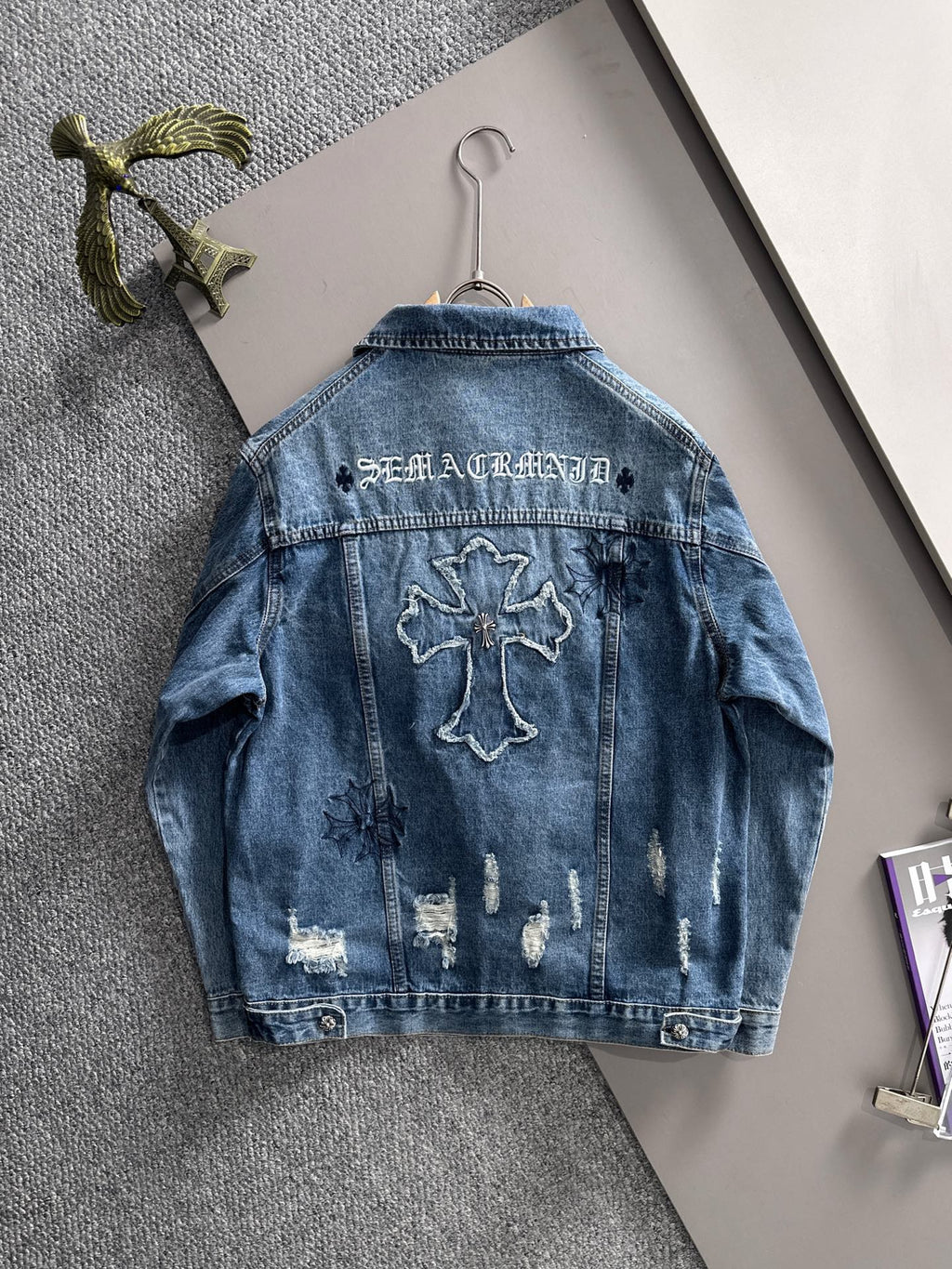 Blue denim jacket back with bold cross embroidery and distressed wash
