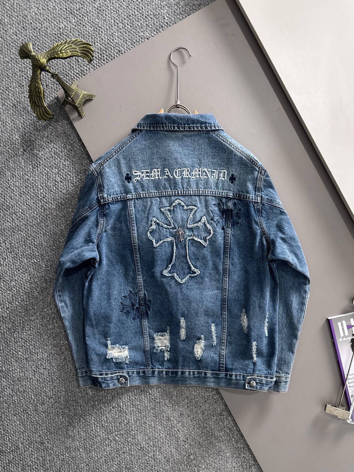 Blue denim jacket back with bold cross embroidery and distressed wash