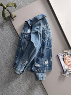 Blue denim jacket back view with embroidered cross patch and distressed finish