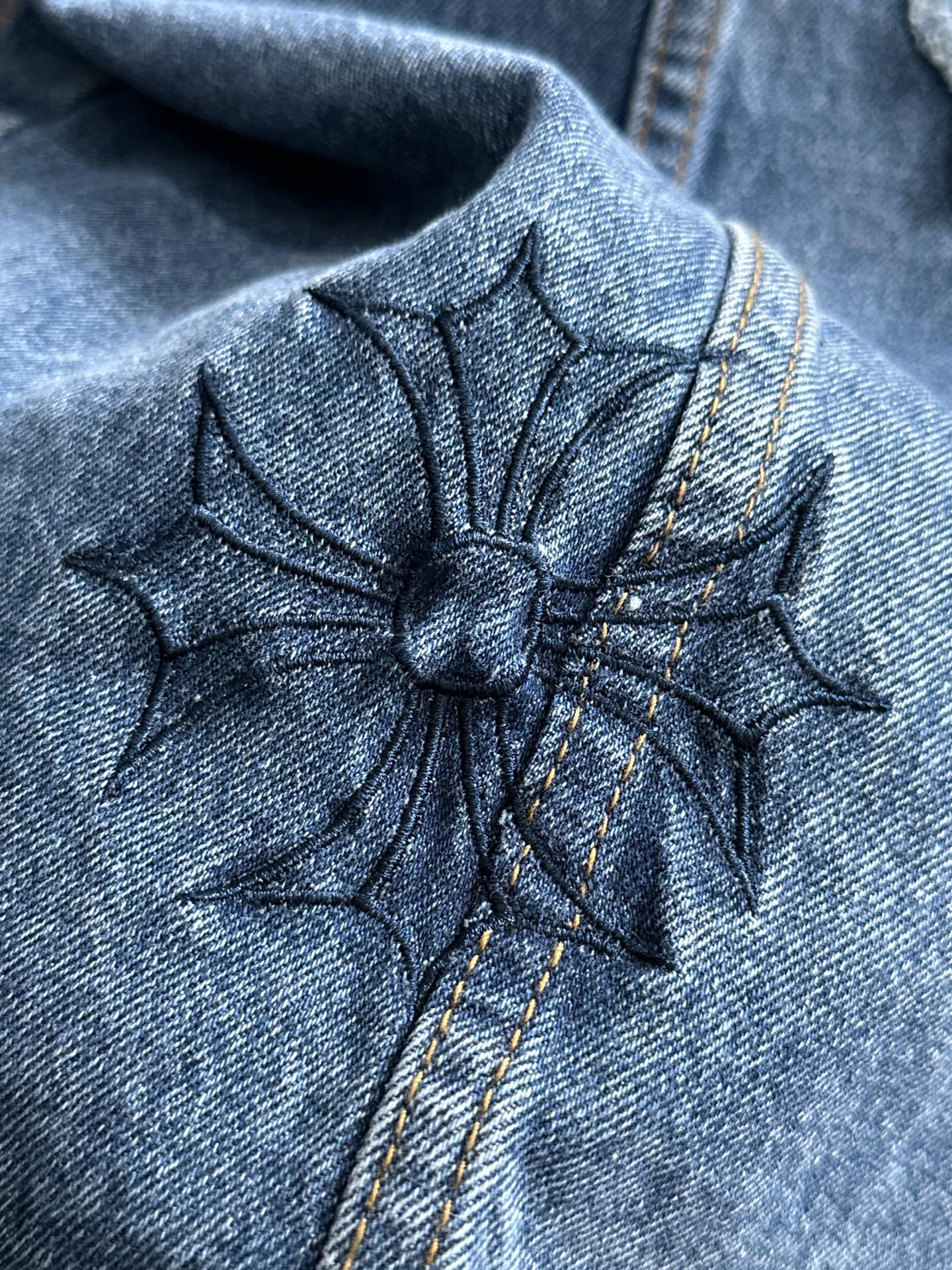 Blue denim jacket close-up of starburst cross embroidery on the yoke