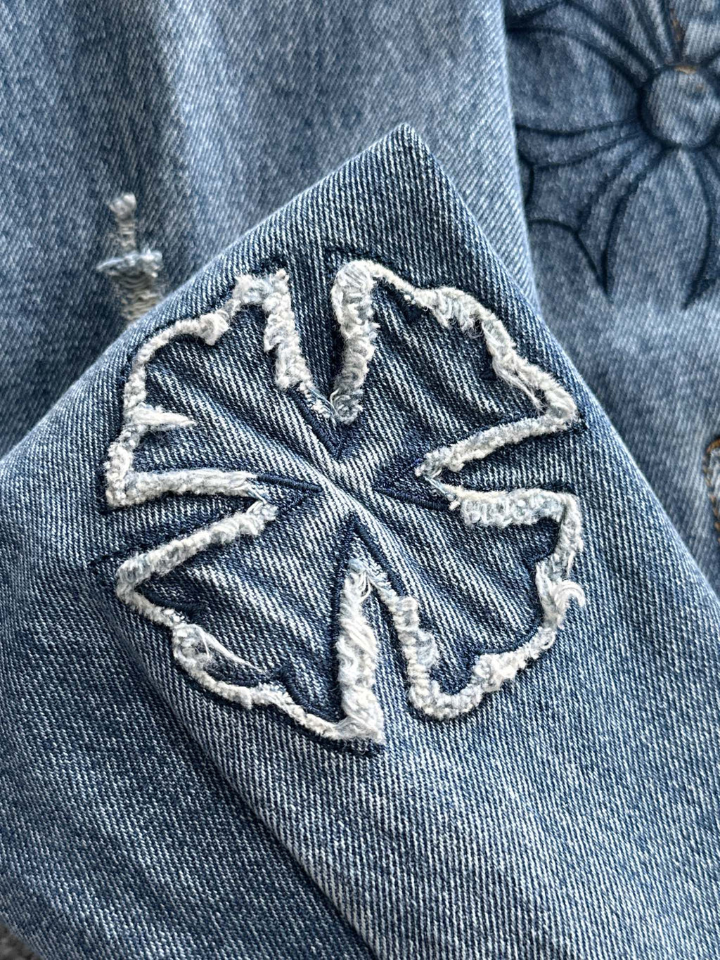 Blue denim jacket sleeve with oversized embroidered snowflake-style emblem