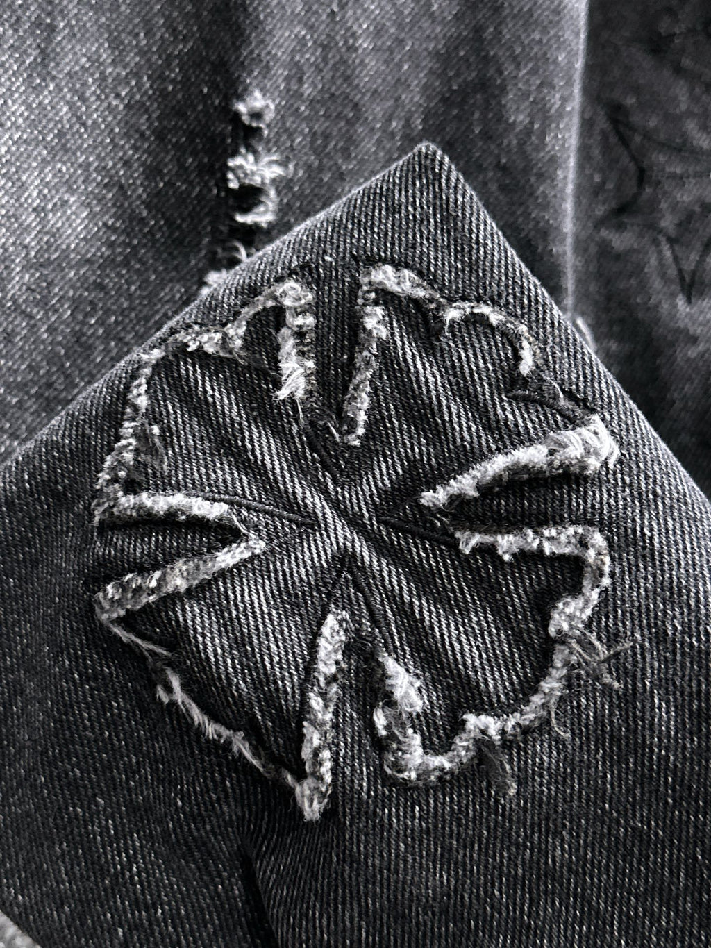 Dark denim jacket shoulder patch with stitched graphic and worn distressed texture