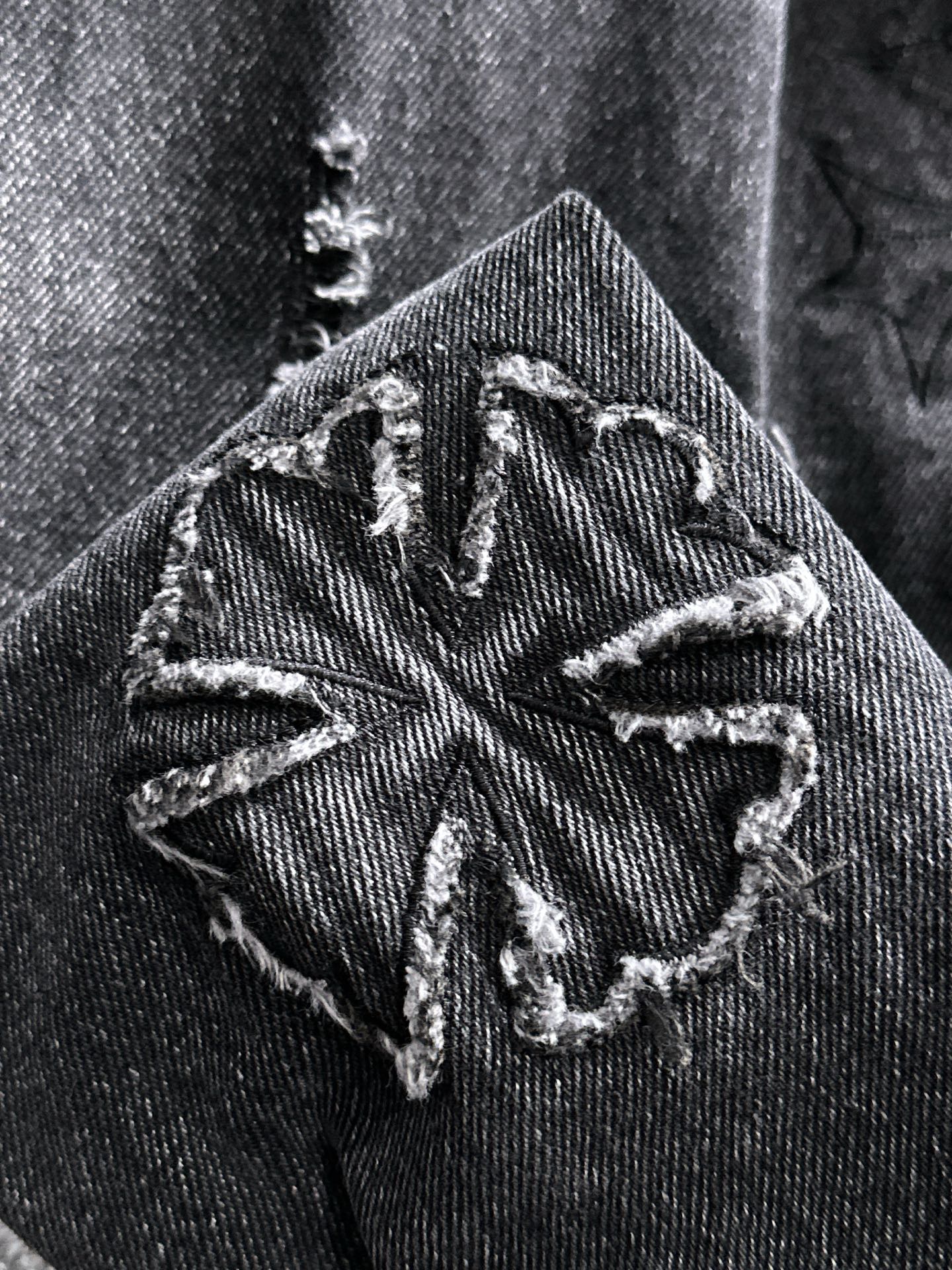Dark denim jacket shoulder patch with stitched graphic and worn distressed texture