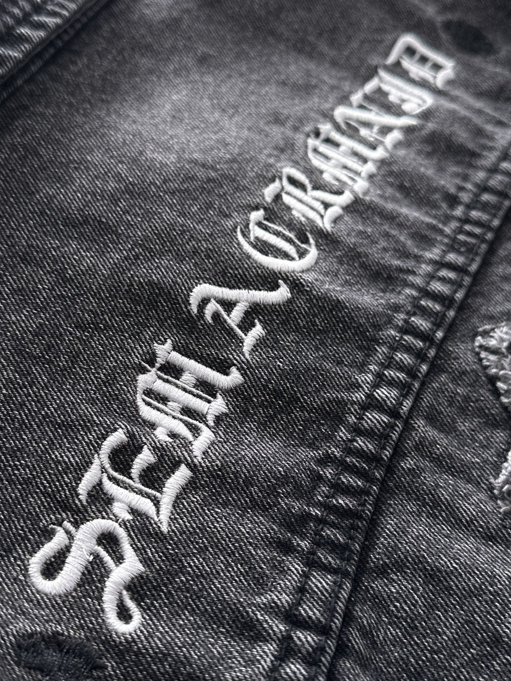 Dark denim jacket graphic embroidery on sleeve cuff with distressed lettering