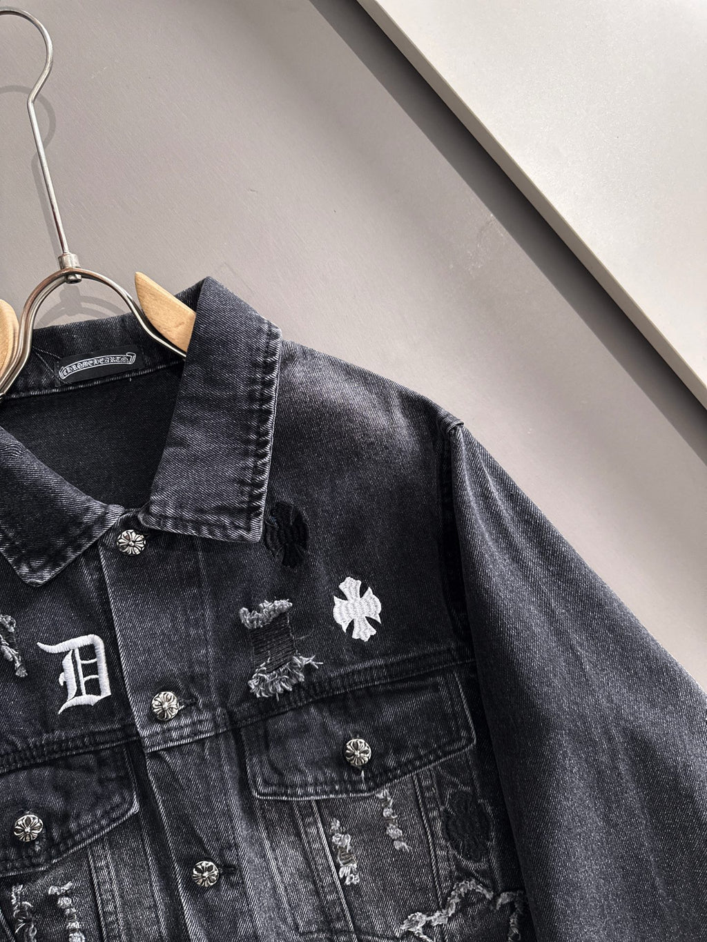Dark denim jacket close-up with stand collar and embroidered chest patches