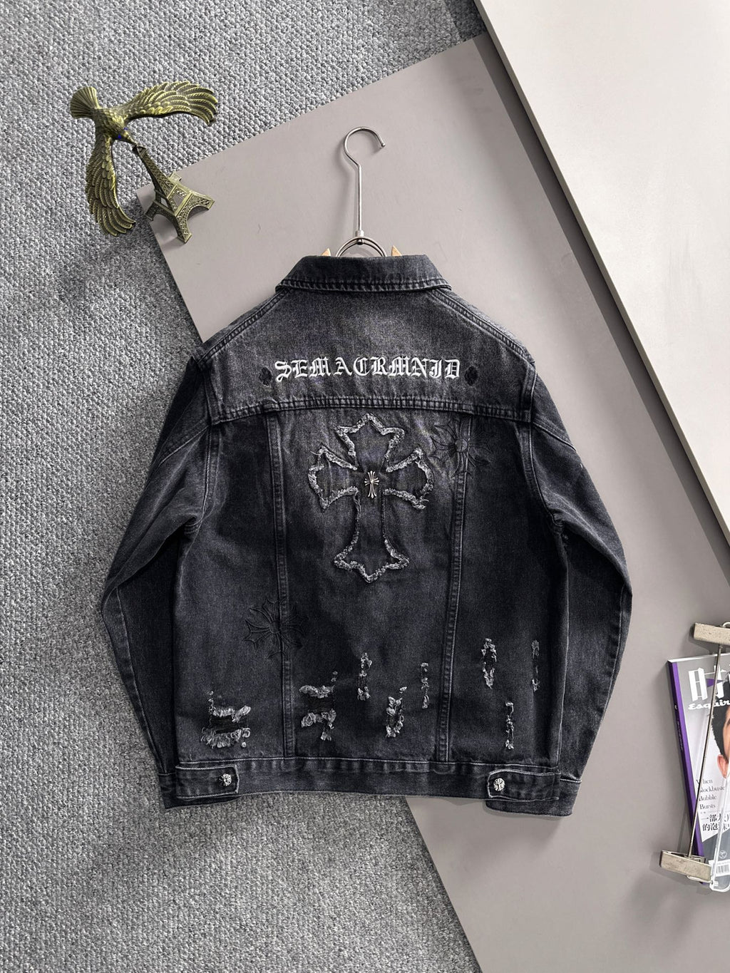 Dark denim jacket back view with embroidered lettering and distressed graphic patches
