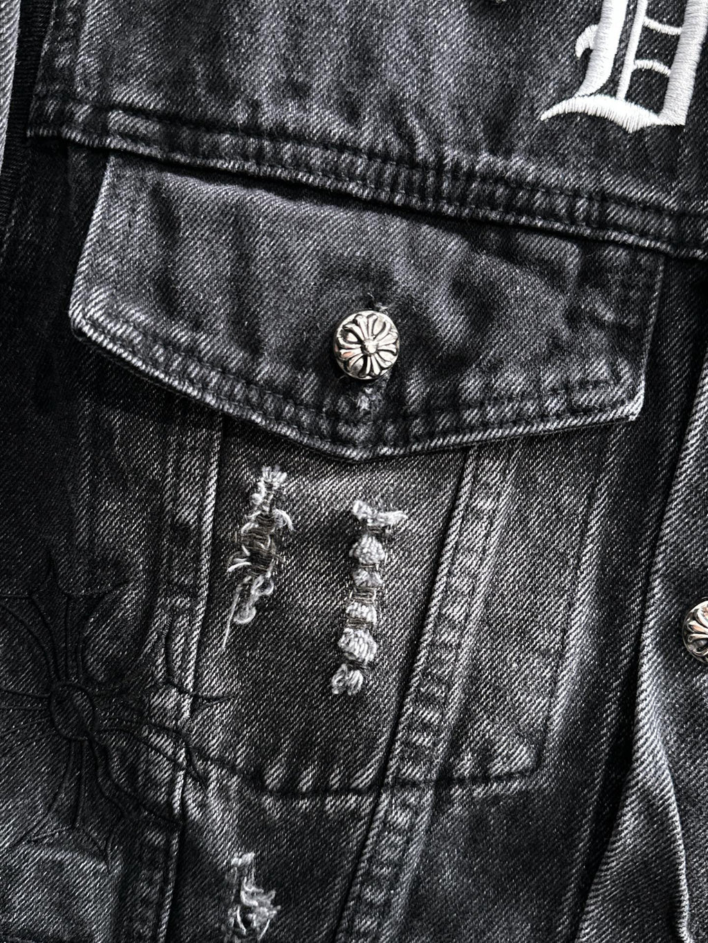 Dark denim jacket front yoke with button and embroidered decorative appliques