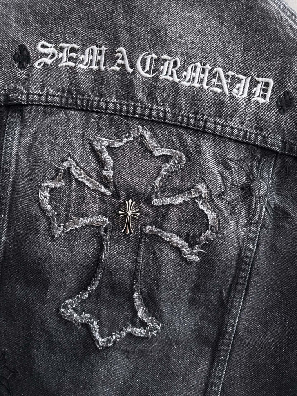 Dark denim jacket back yoke with embroidered star-like patches and worn stitching