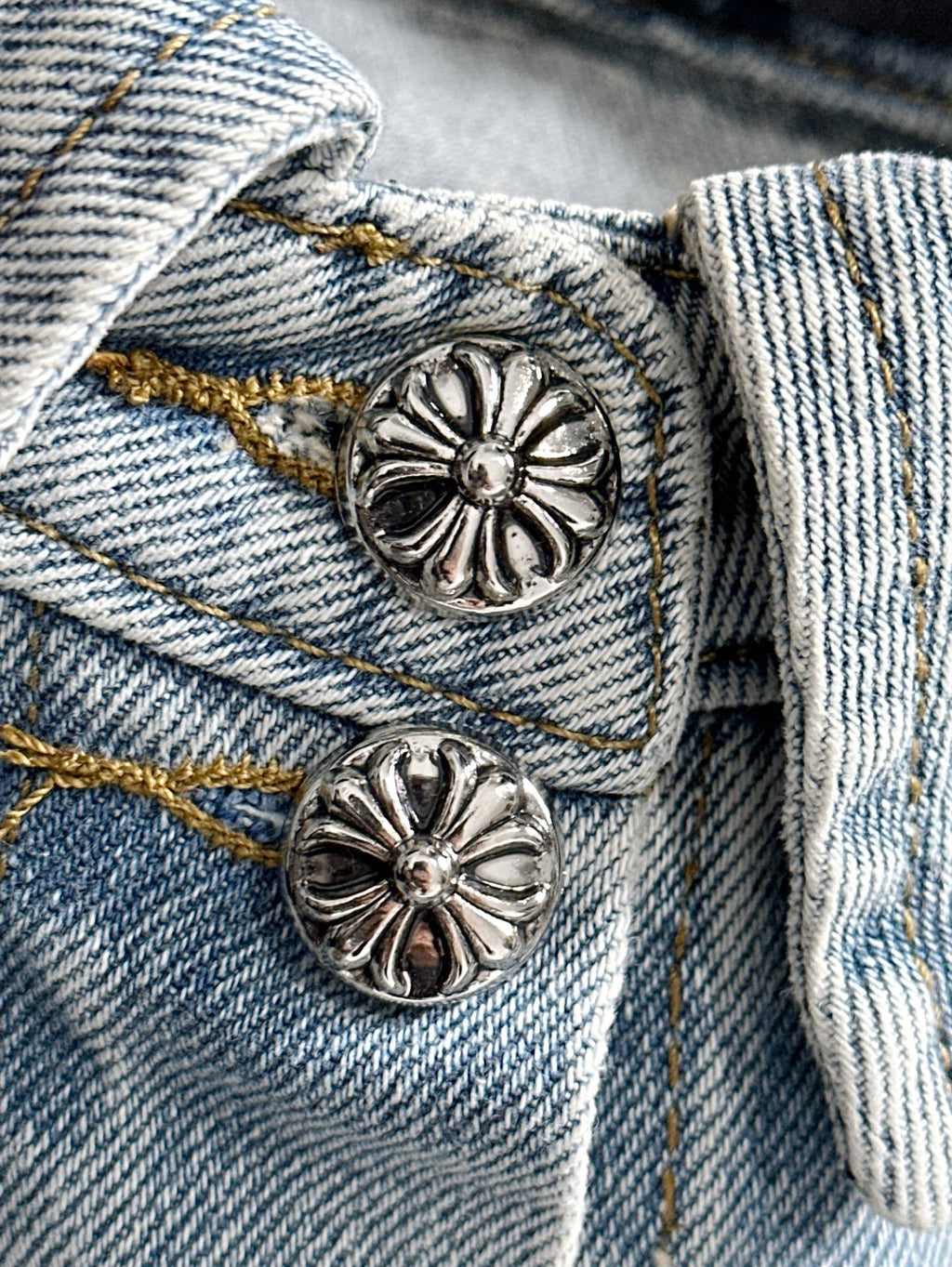 Close-up light blue denim jacket with silver flower buttons on flap pockets
