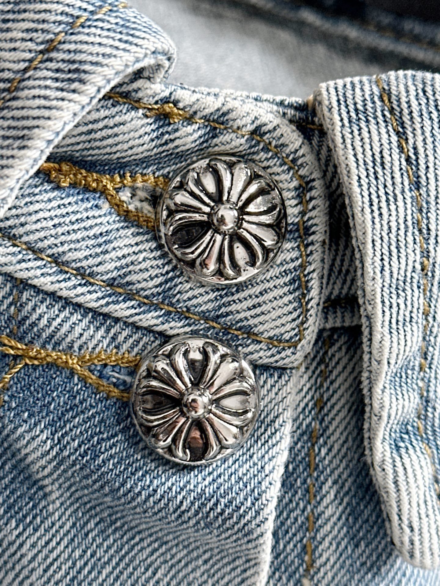 Close-up light blue denim jacket with silver flower buttons on flap pockets