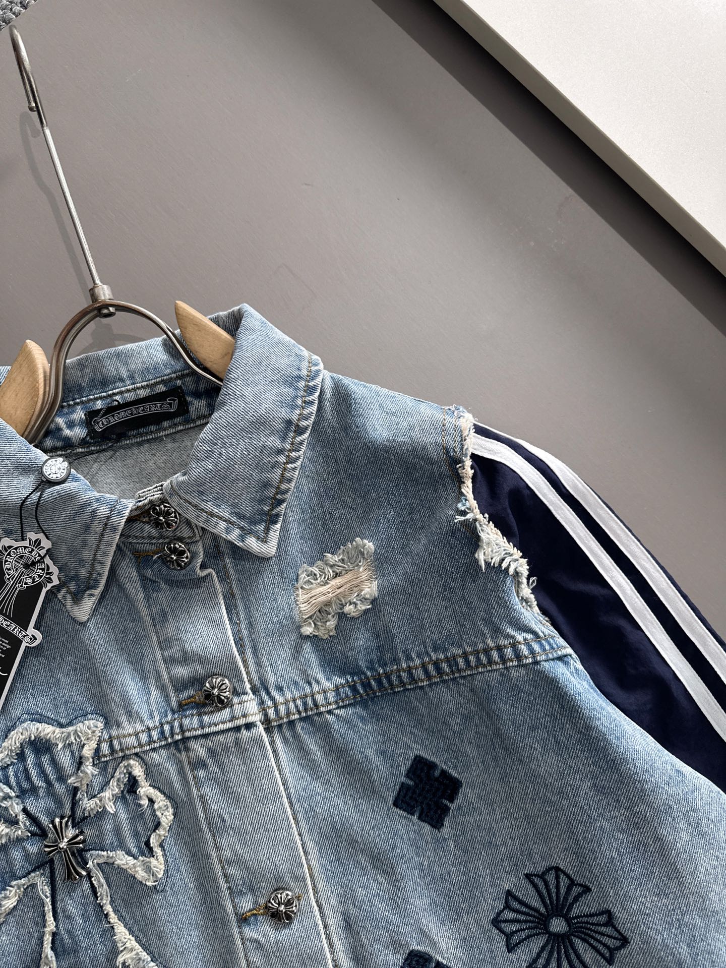 Light blue denim jacket with embroidered chest details and dark navy side stripe panels