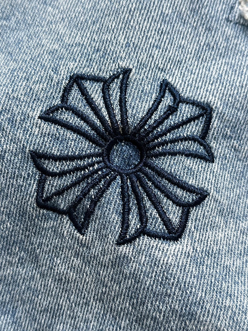 Light blue denim jacket with navy stitched flower emblem in fabric