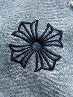 Light blue denim jacket with navy stitched flower emblem in fabric