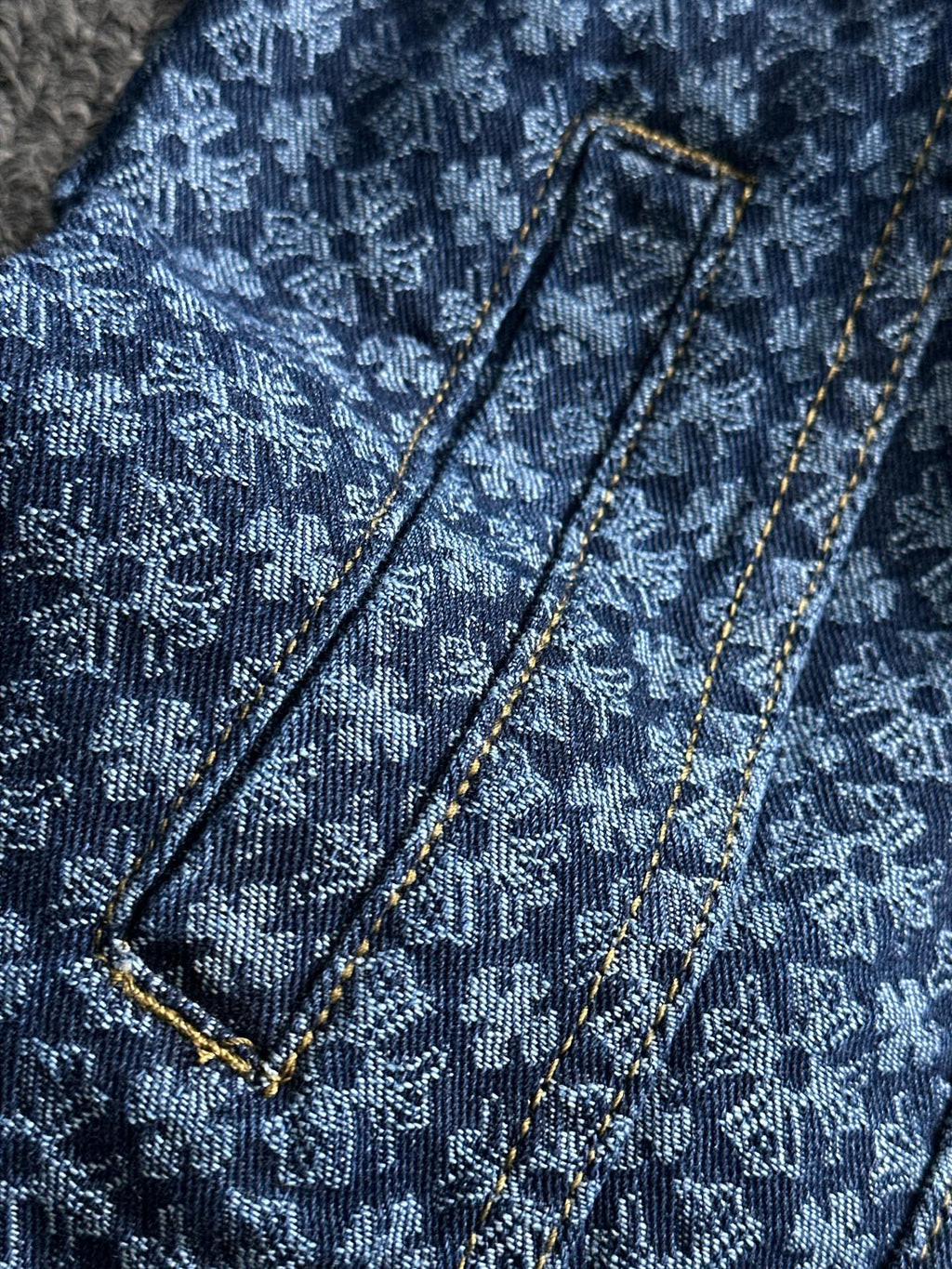 Blue patterned denim jacket with shoulder straps and gold-trimmed seams detail