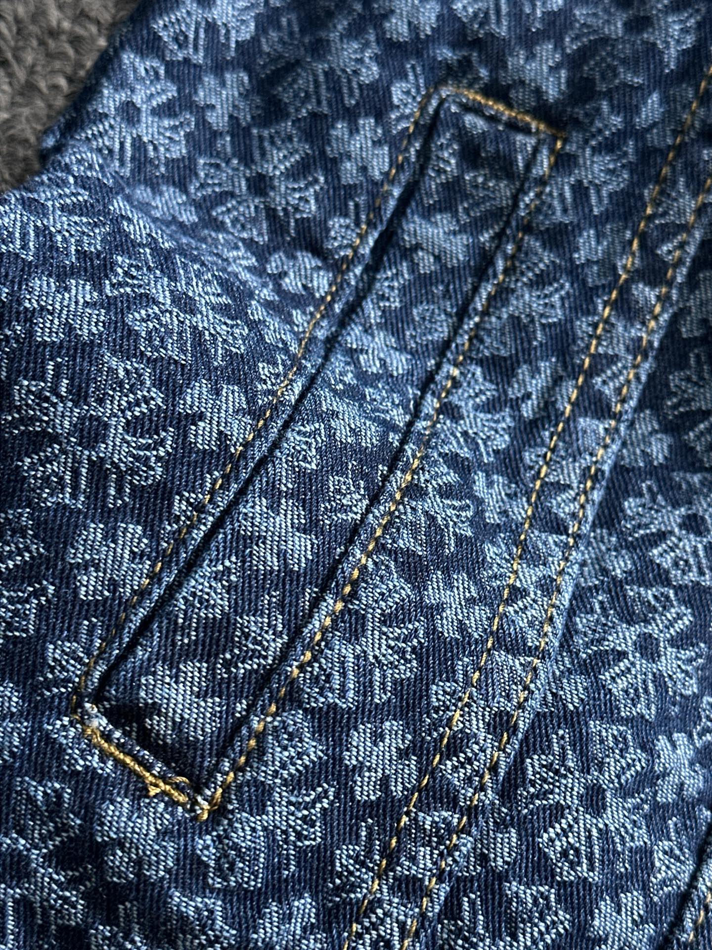 Blue patterned denim jacket with shoulder straps and gold-trimmed seams detail