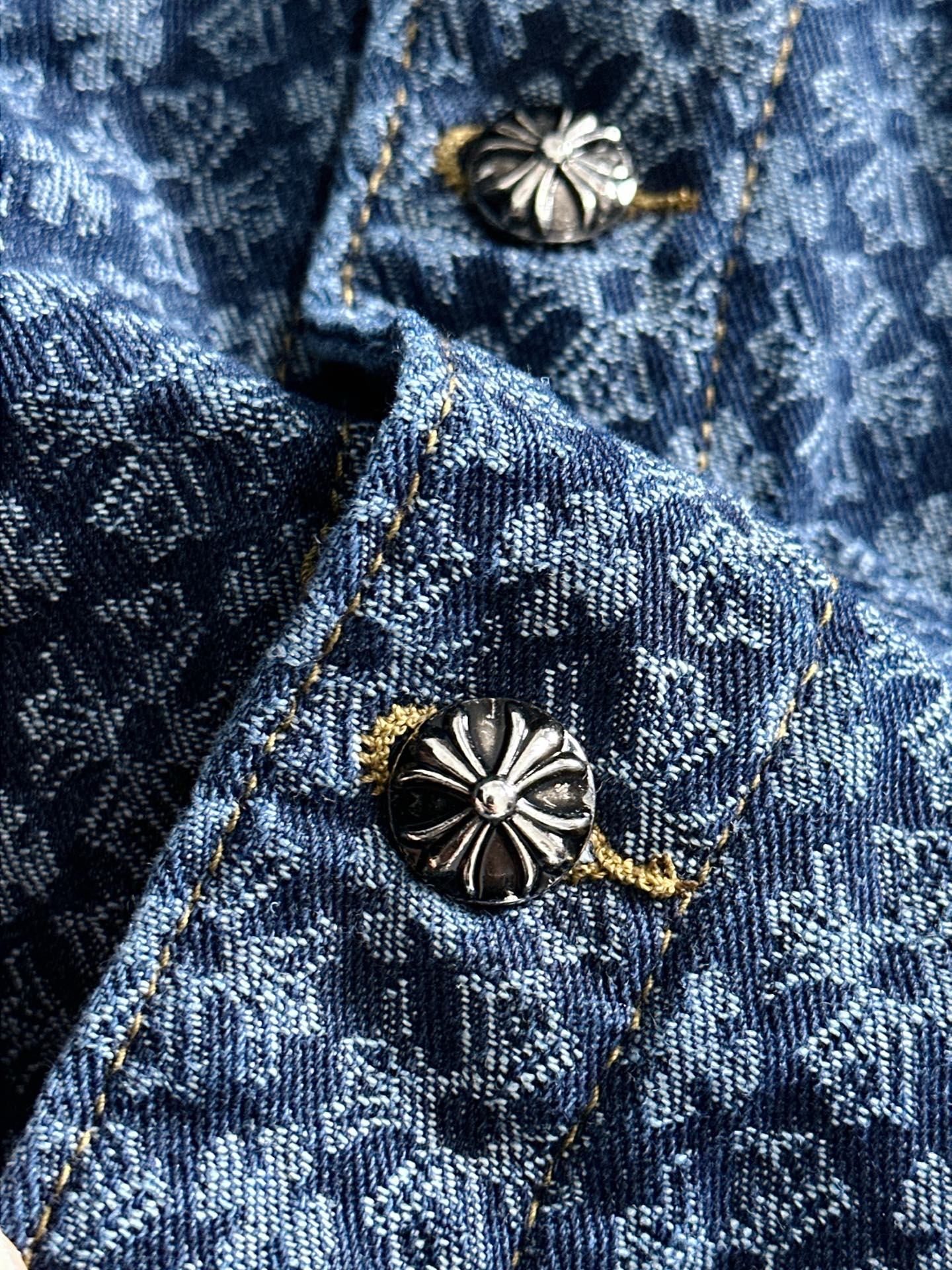 Blue patterned denim jacket neckline with decorative buttons and gold accents