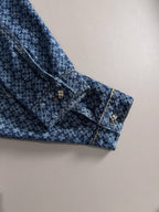 Blue patterned denim jacket sleeve cuff with decorative buttons and gold trim