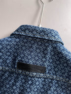 Blue patterned denim jacket back yoke with black brand patch near collar