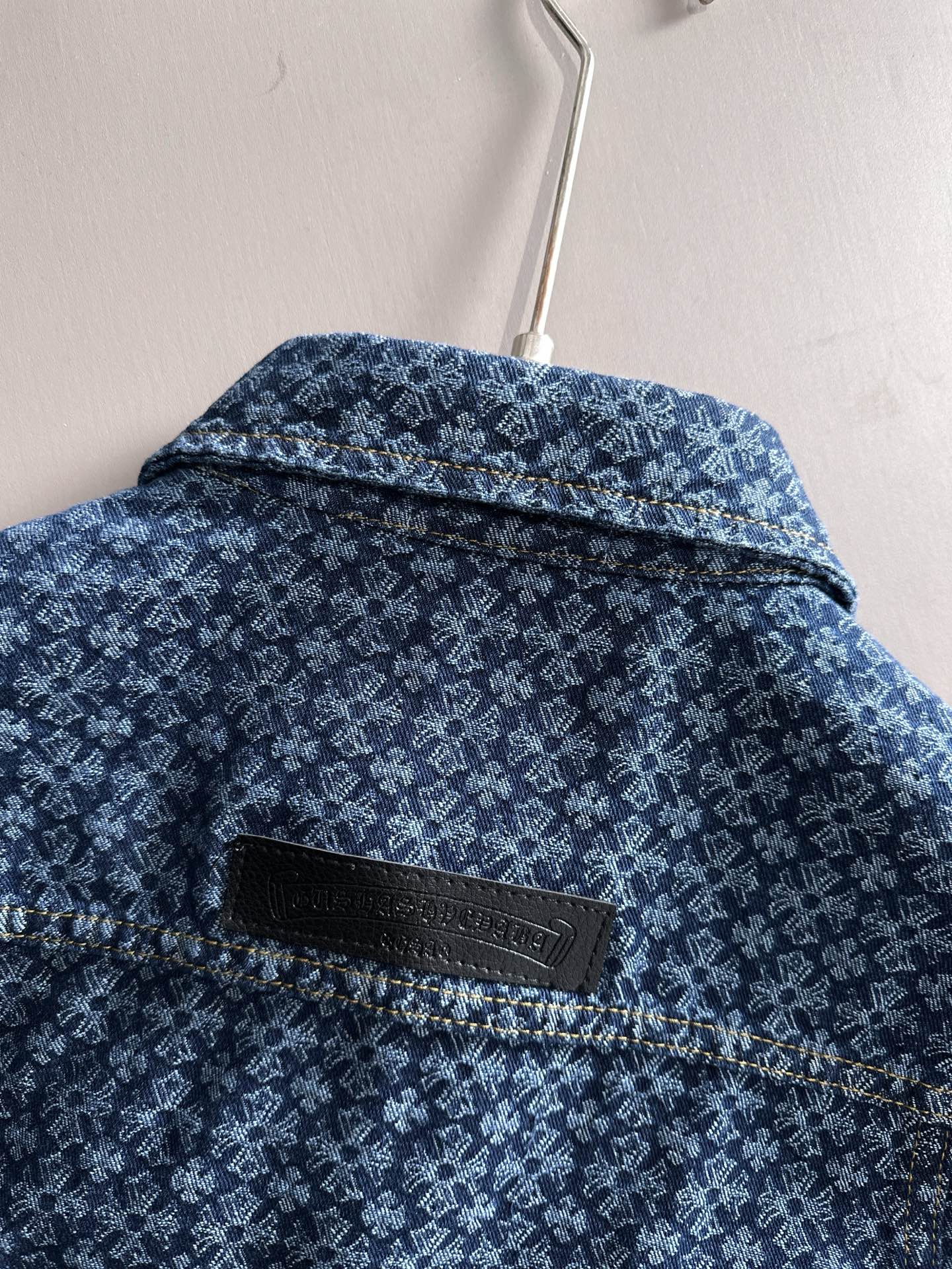 Blue patterned denim jacket back yoke with black brand patch near collar