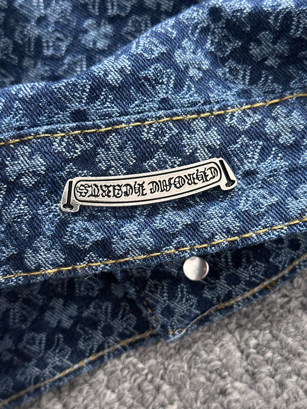 Blue denim jacket label on chest pocket, gold topstitching and button closure