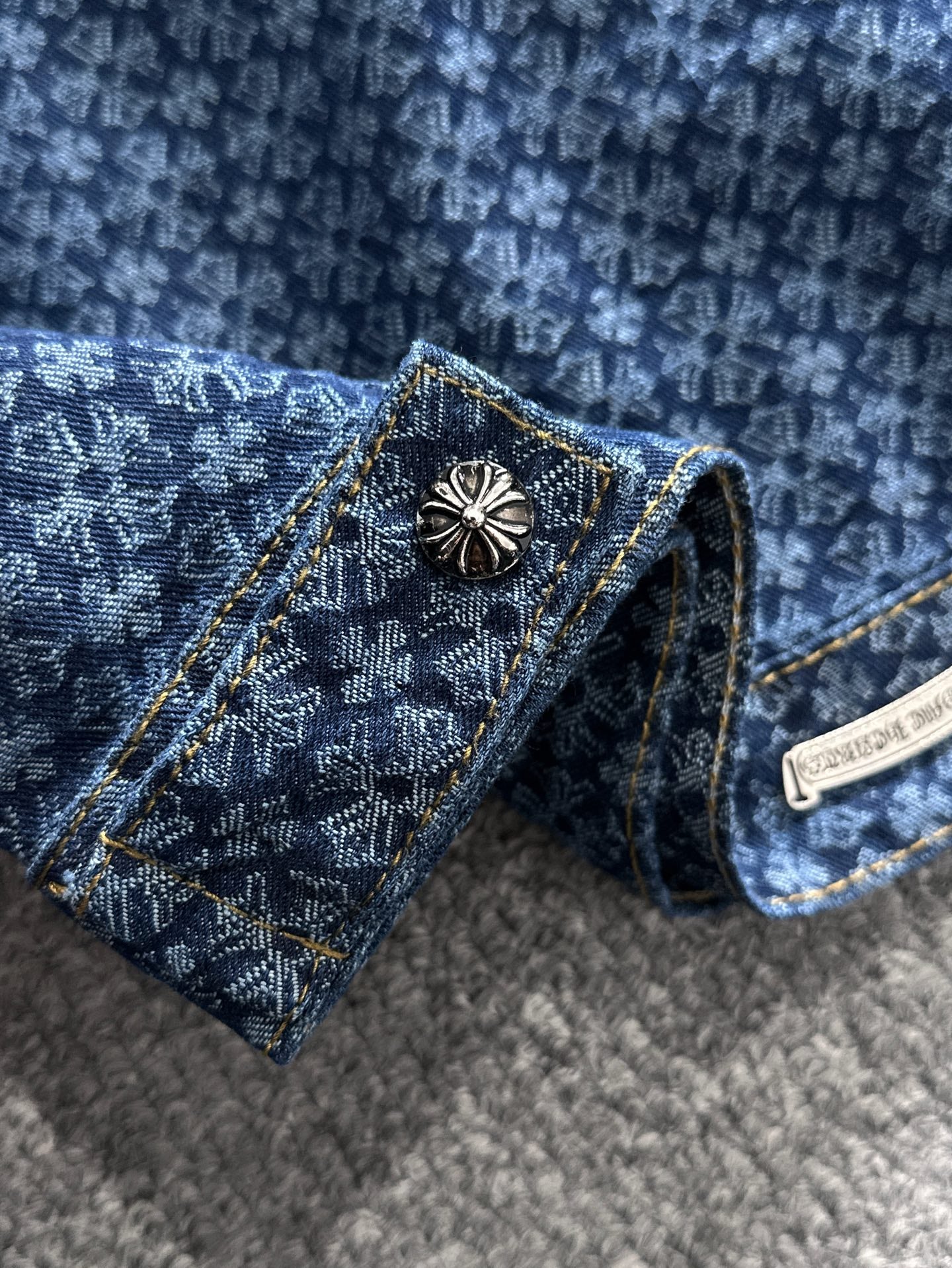Blue patterned denim jacket chest pocket with decorative button and gold trim