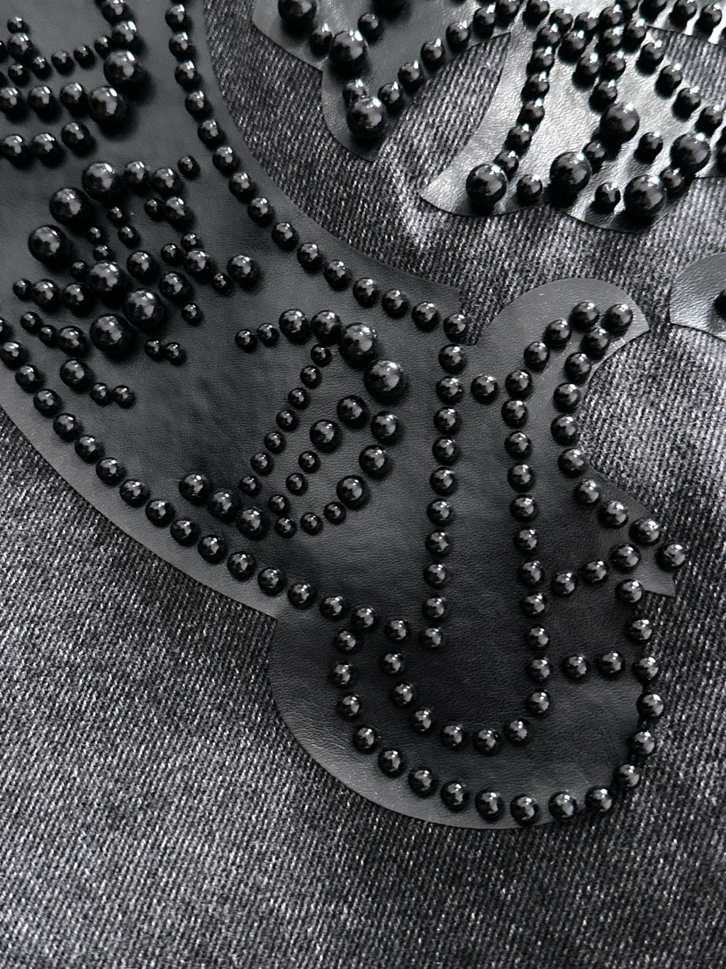 Studded heart-shaped emblem close-up on denim with bead outline and small rivets