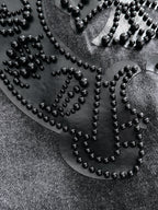 Studded heart-shaped emblem close-up on denim with bead outline and small rivets