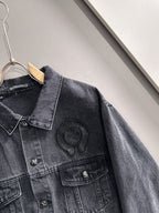 Dark denim jacket shoulder and sleeve detail with studded emblem on the chest