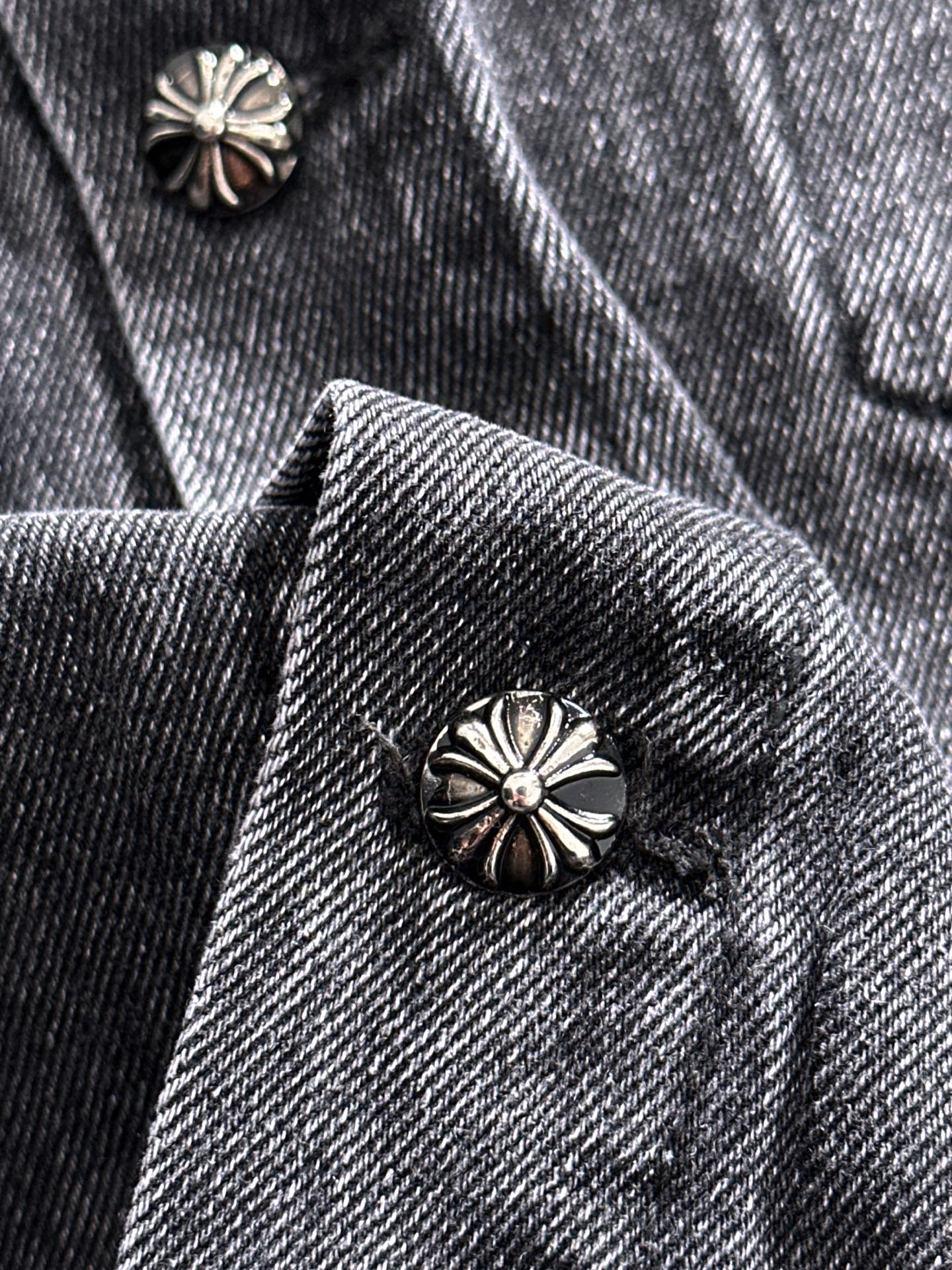 Denim jacket lapel and inner collar with metal flower button and patterned trim