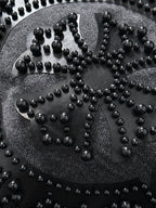 Large studded emblem close-up on denim, with raised beads forming an ornate pattern