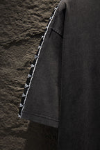 Balenciaga black T-shirt side view with white logo tape along sleeve edge