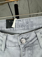 Light blue denim jeans waist close-up with Versace coin emblem button