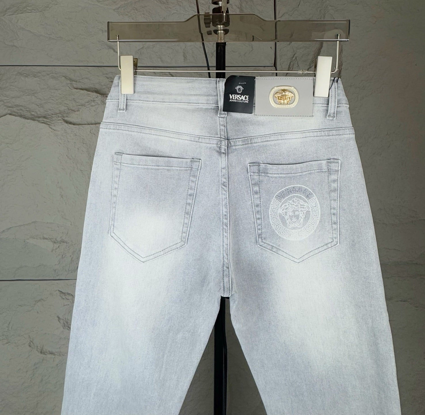 Light-wash denim jeans with back pockets, top button, and centered brand patch