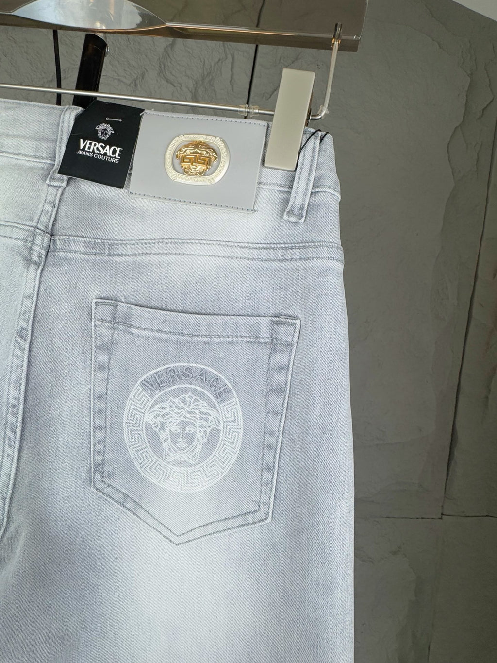 Light blue denim jeans close-up with Versace patch and embroidered logo on pocket