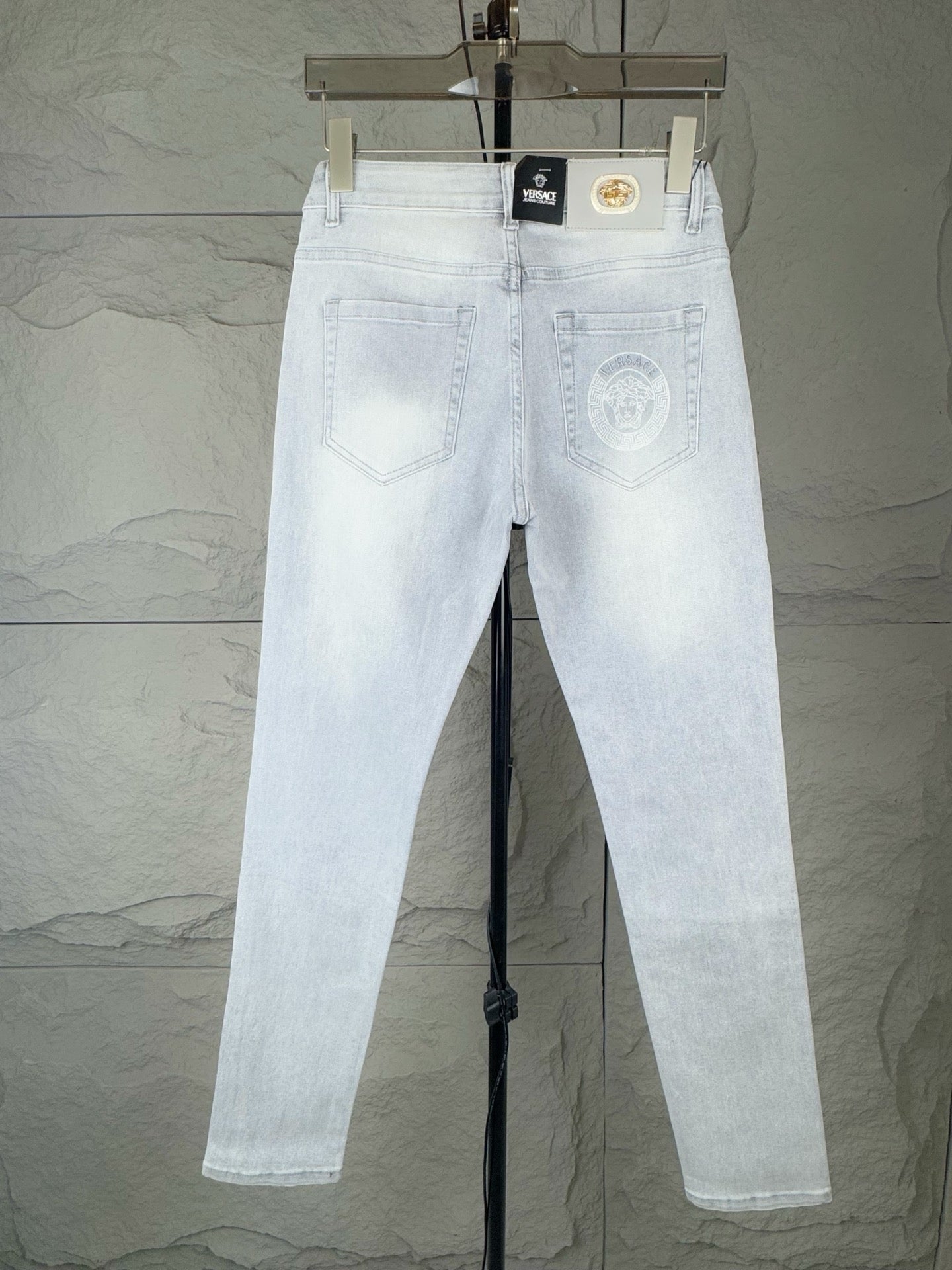 Light-wash denim jeans with back yoke stitching and embroidered emblem on right pocket