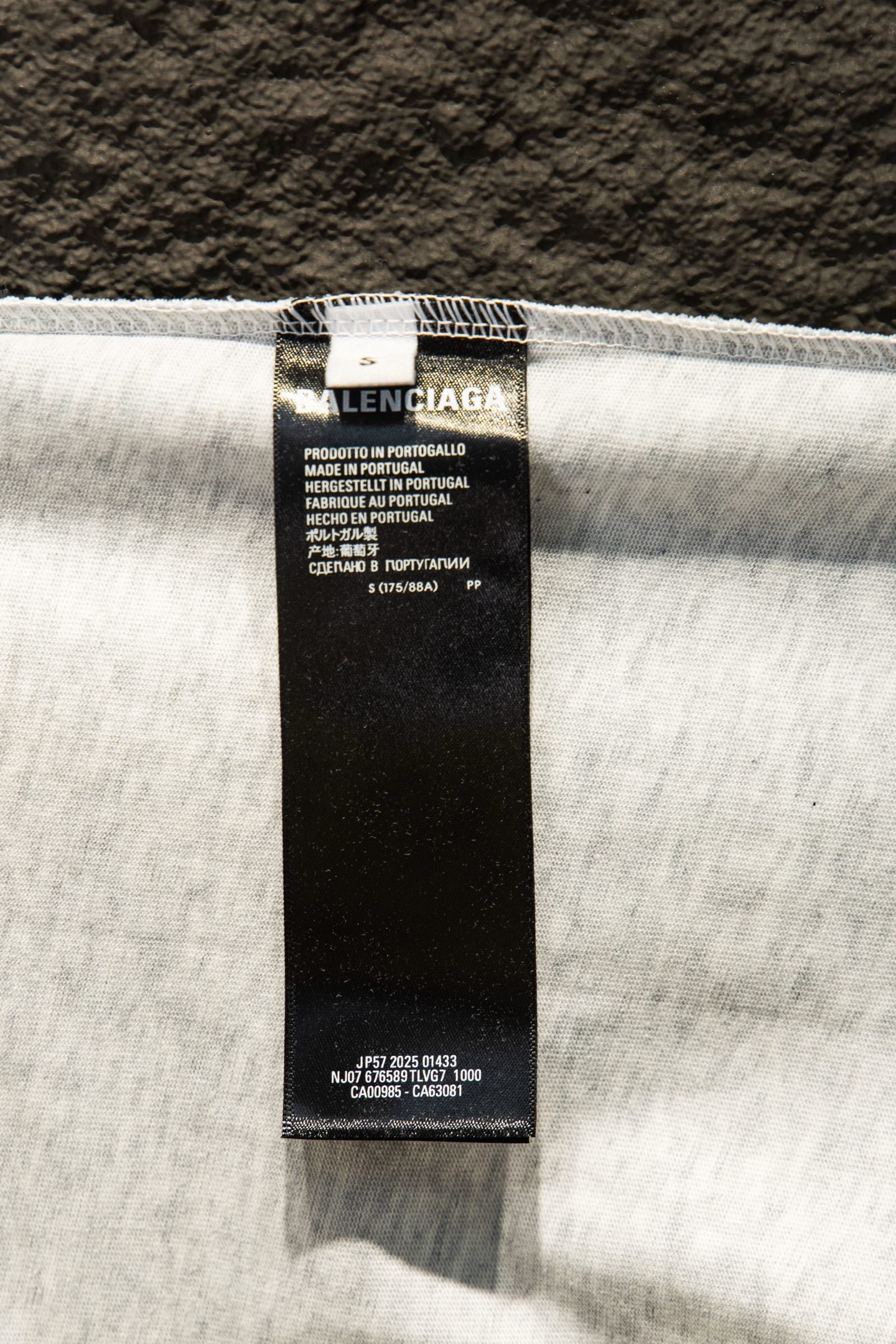 White T-shirt with black size and care label at top hem