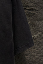 Black T-shirt sleeve and side seam view, hanging on wall