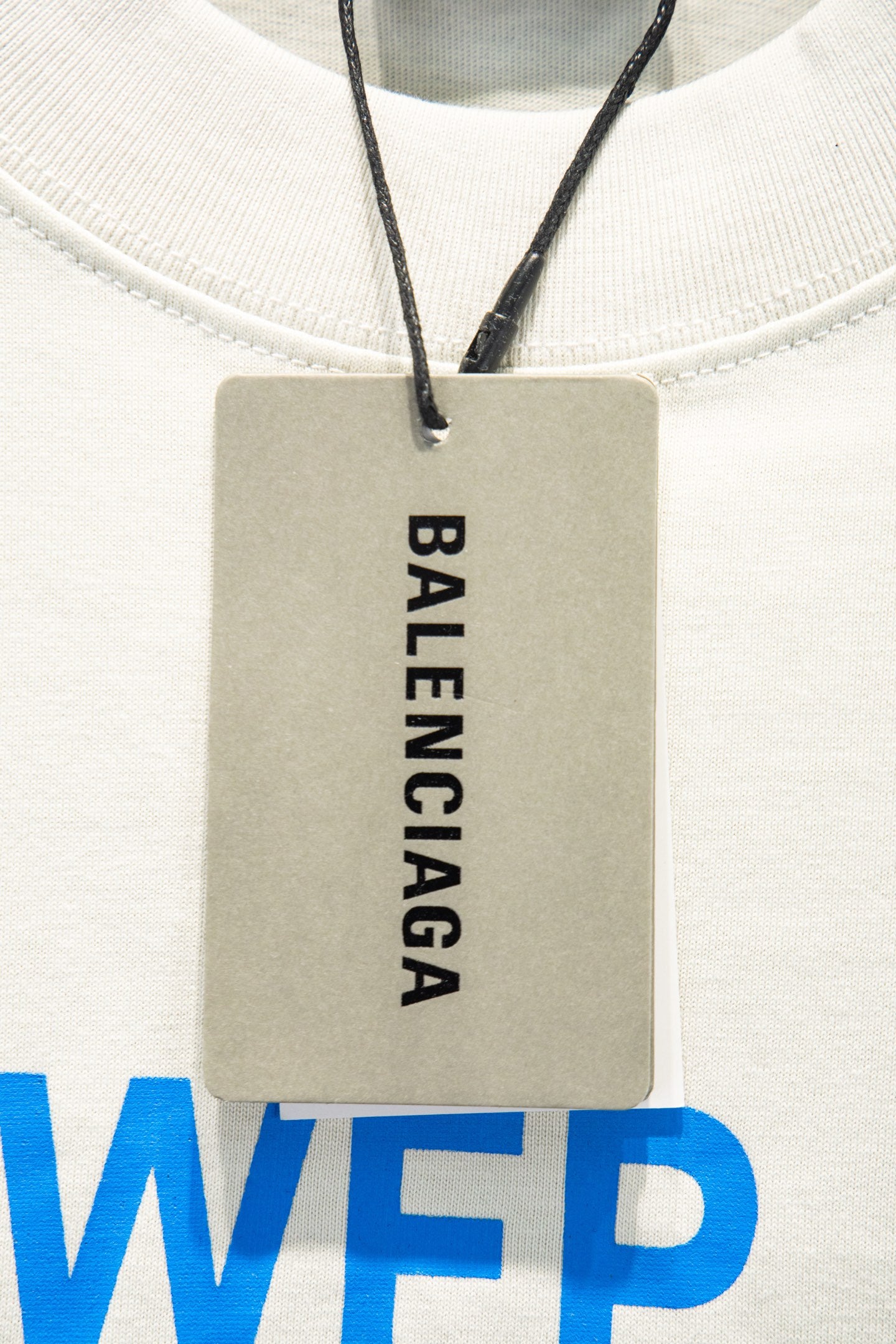 White T-shirt neckline with hanging BALENCIAGA label tag and blue WFP print
