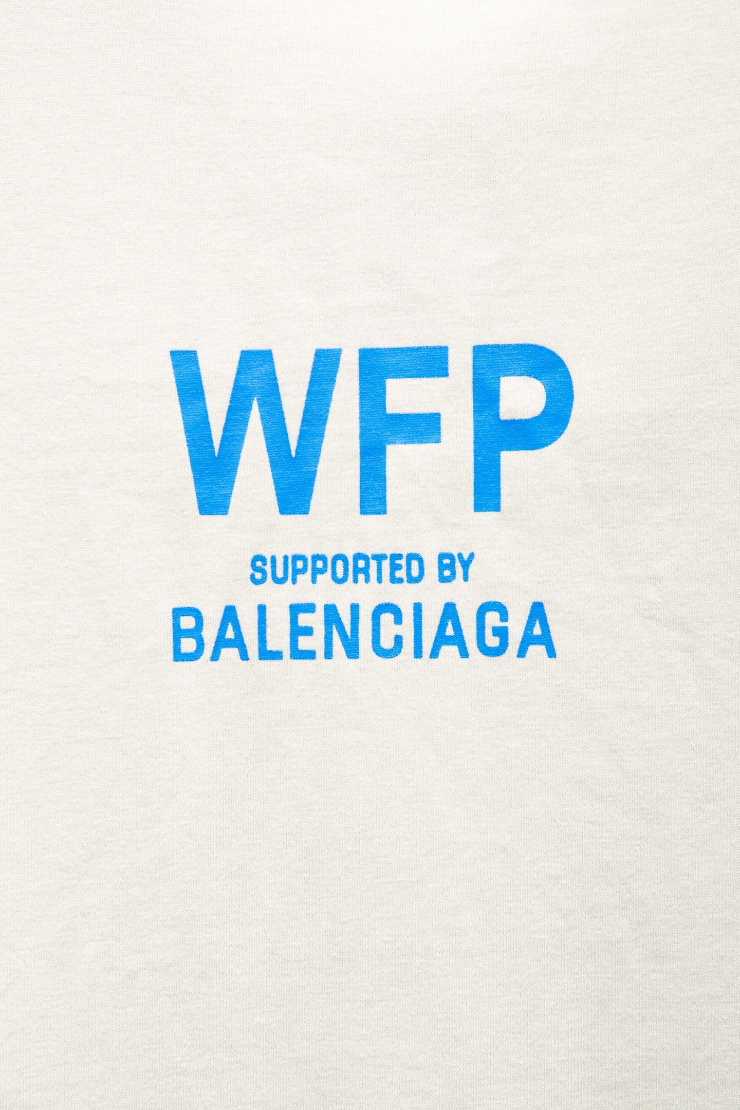White T-shirt close-up with large blue WFP supported by BALENCIAGA text