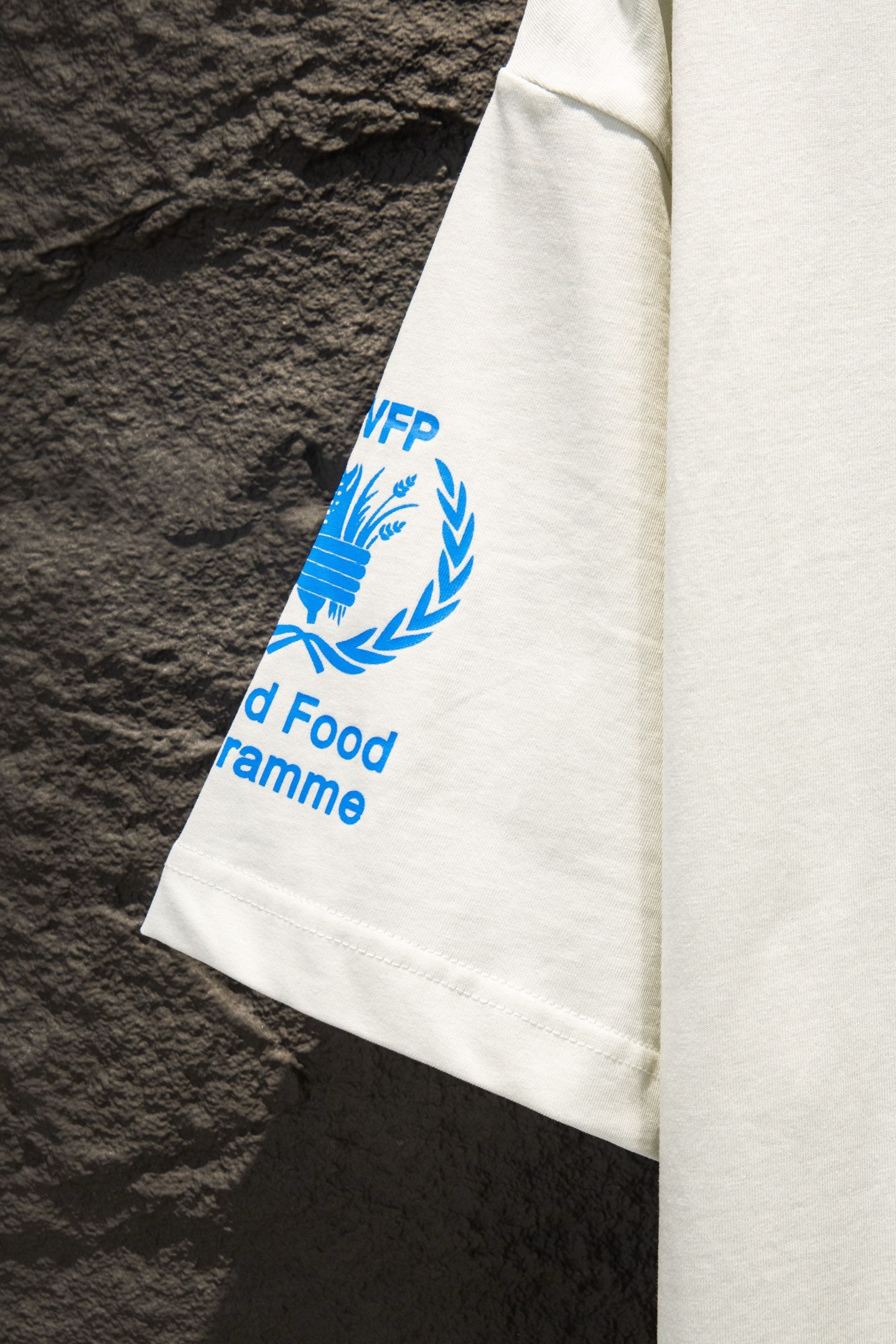 White T-shirt sleeve with blue laurel WFP text graphic