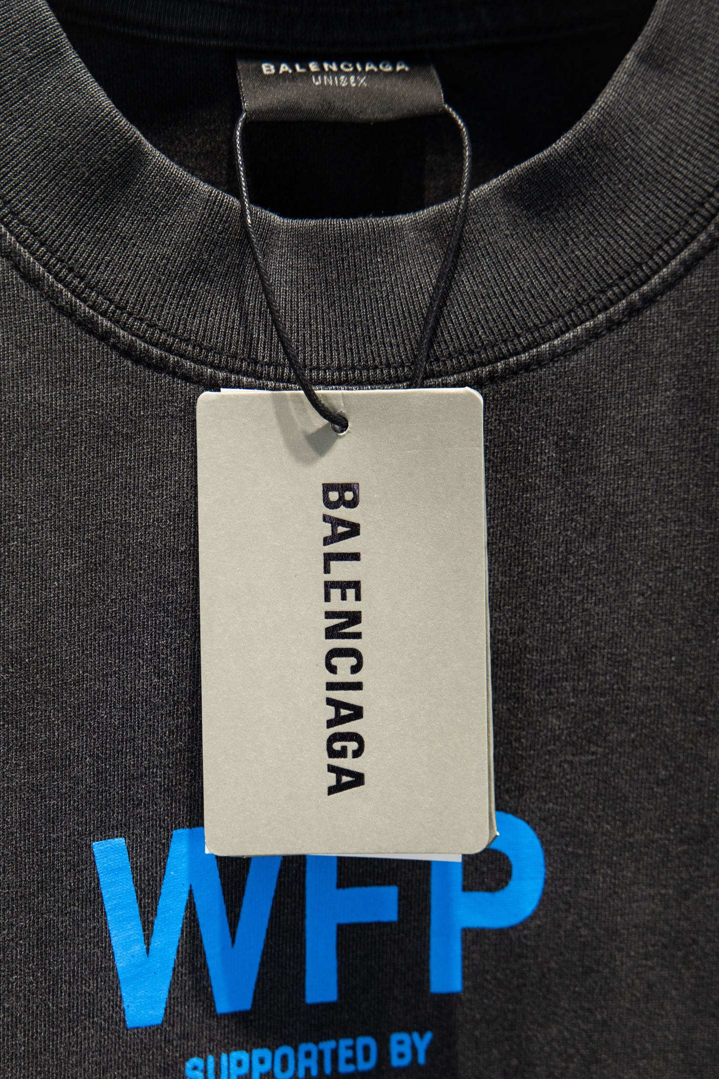 Gray T-shirt neckline with “BALENCIAGA” tag and blue “WFP” logo